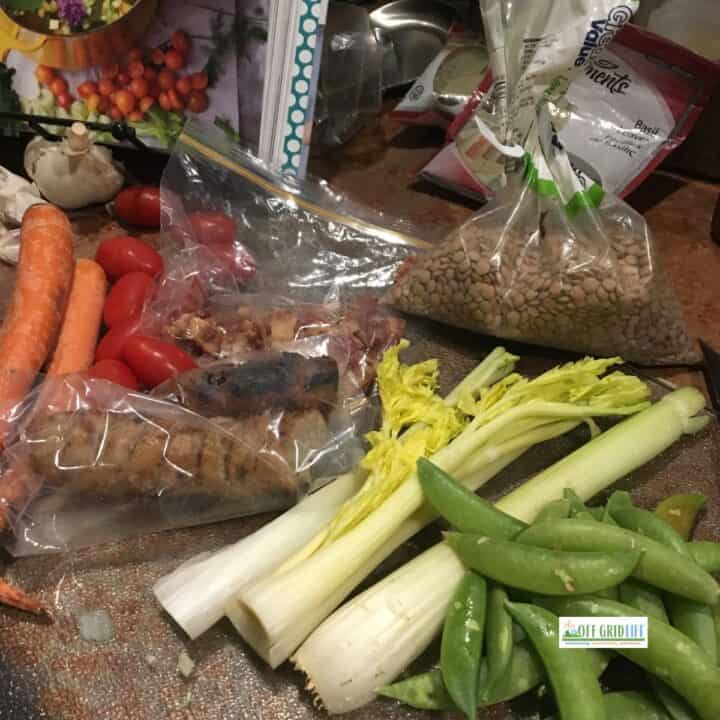 Celery, peas, tomatoes, lentils, sausages, and carrots on counter to make soup to save money