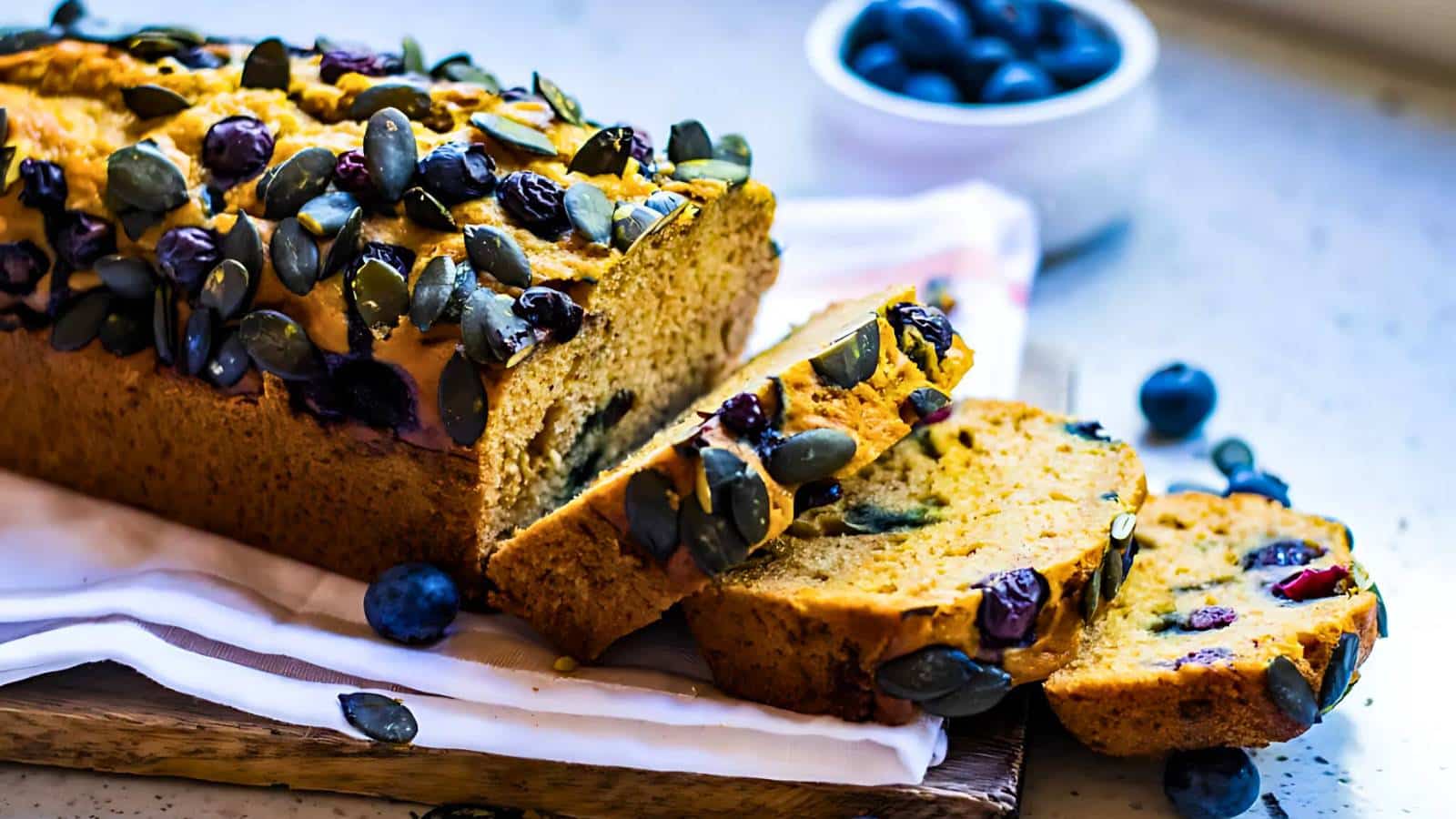 Sliced banana bread with chocolate chips next to a knife on parchment paper.