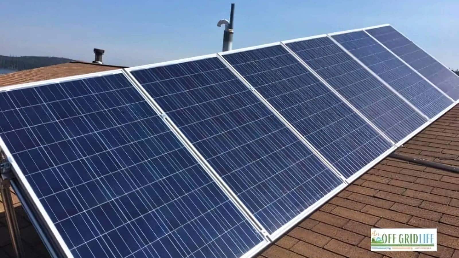 Solar panels installed on a brown sloped roof under a clear sky. Logo in the bottom right corner reads "OFF GRID LIFE.