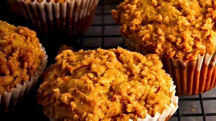 Close-up of muffins topped with a crumbly, golden-brown streusel on a cooling rack.