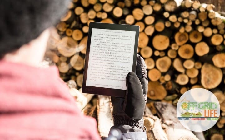 Person holding Kindle standing in front of a stack of firewood