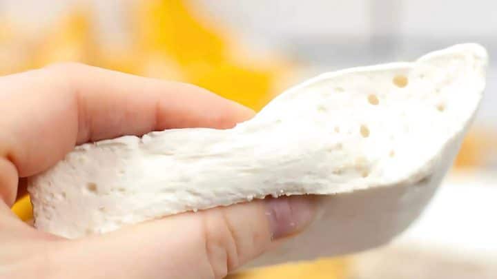 A hand squeezing a piece of soft white homemade marshmallows.