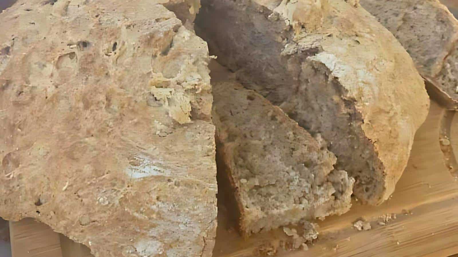 Sliced homemade bread with a crusty exterior on a wooden cutting board.