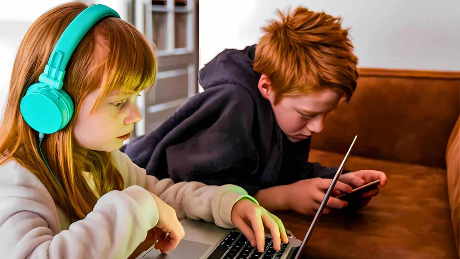 Two children wearing hats are exploring in a forested area. One child is bending down looking at the ground while the other stands nearby, holding a stick.