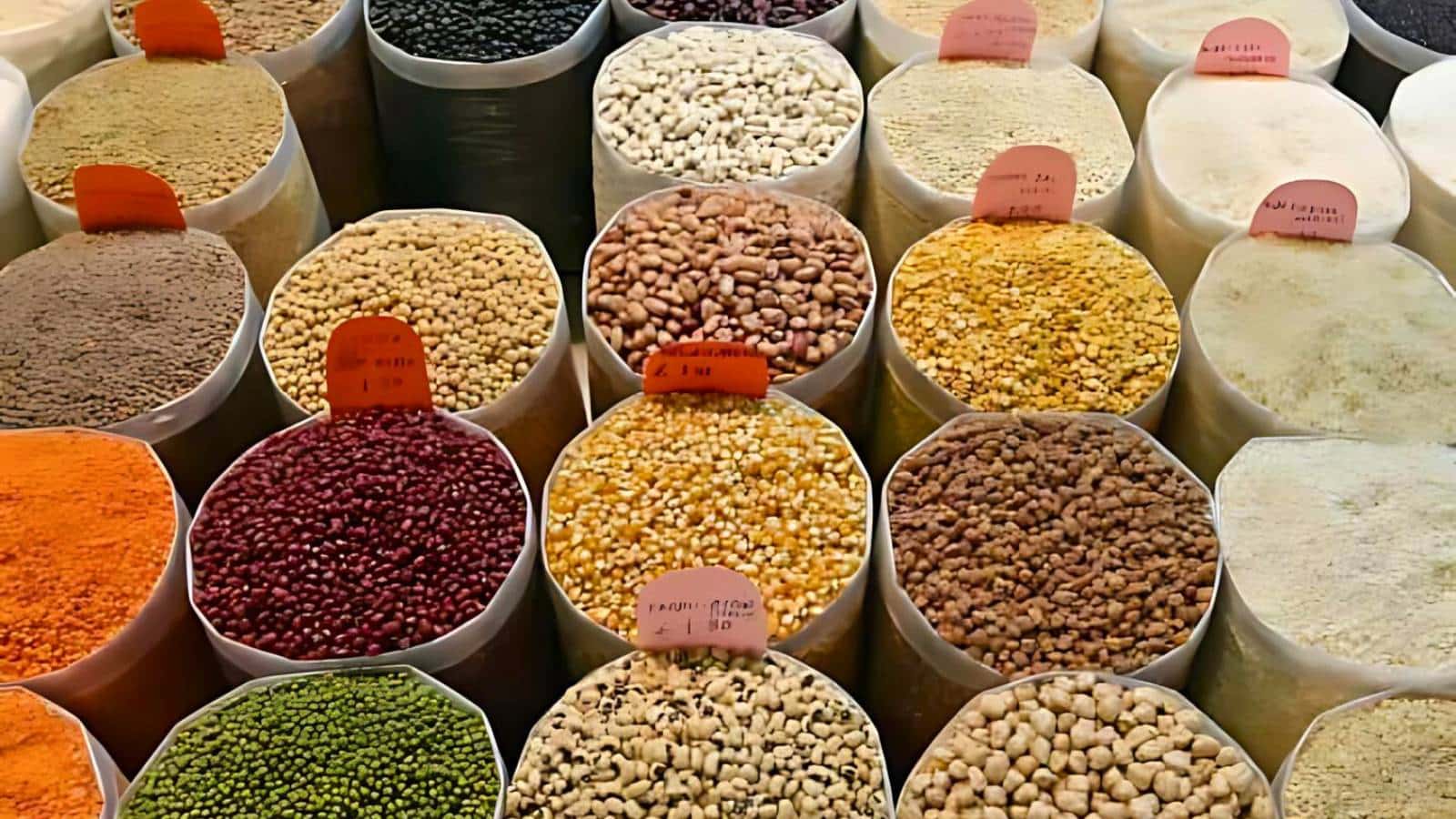 Various beans and grains in labeled sacks displayed at a market.
