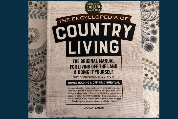 Cover of "The Encyclopedia of Country Living" by Carla Emery, featuring text about homesteading, off-grid survival, and living off the land on a rustic background.