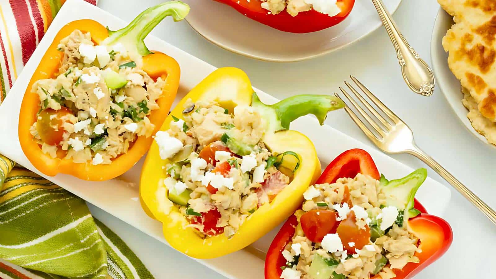 A bowl of creamy potato and vegetable stew with diced ham, accompanied by a plain bread roll on a textured cloth.