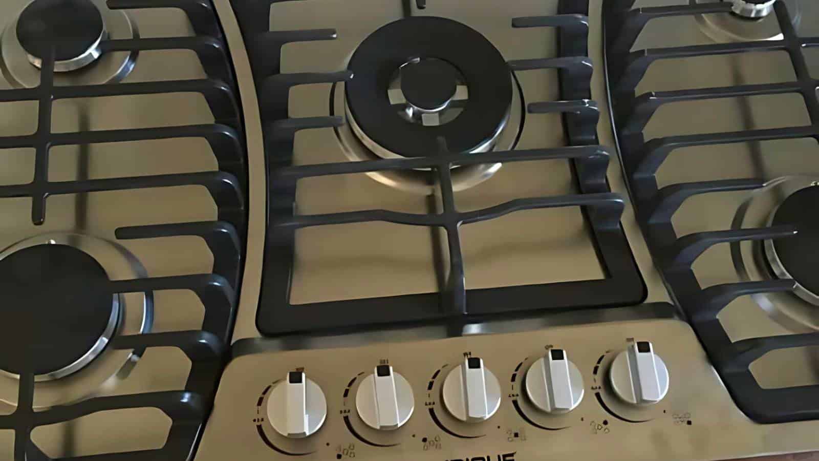 Close-up of a stainless steel gas stove top with five burners and control knobs in the front center.
