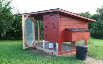 a raised red diy chicken coop with attached chicken run