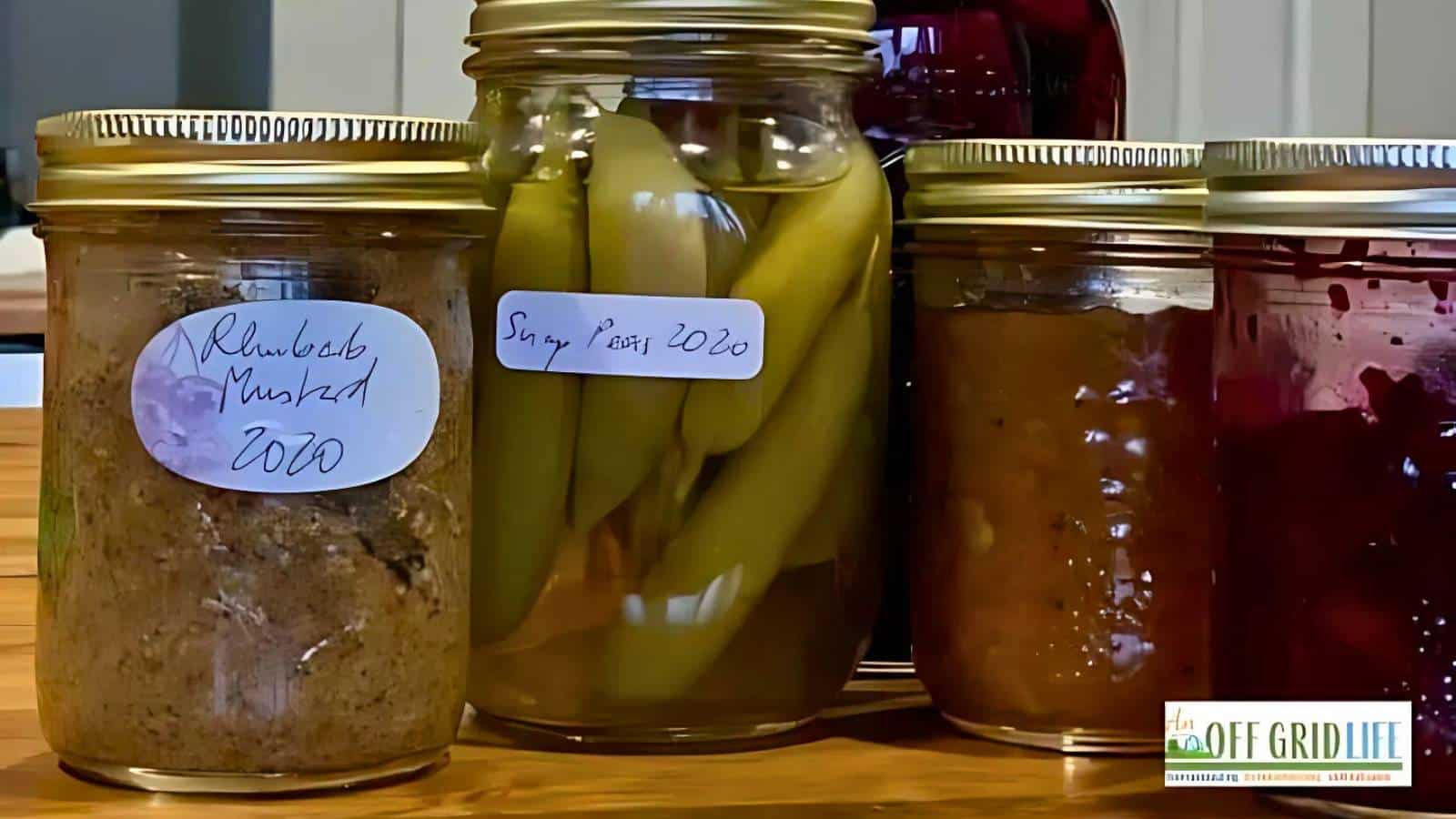 Jars of homemade preserves on a table, labeled as Rhubarb Mustard 2020, Sugar Peas 2020, and others.