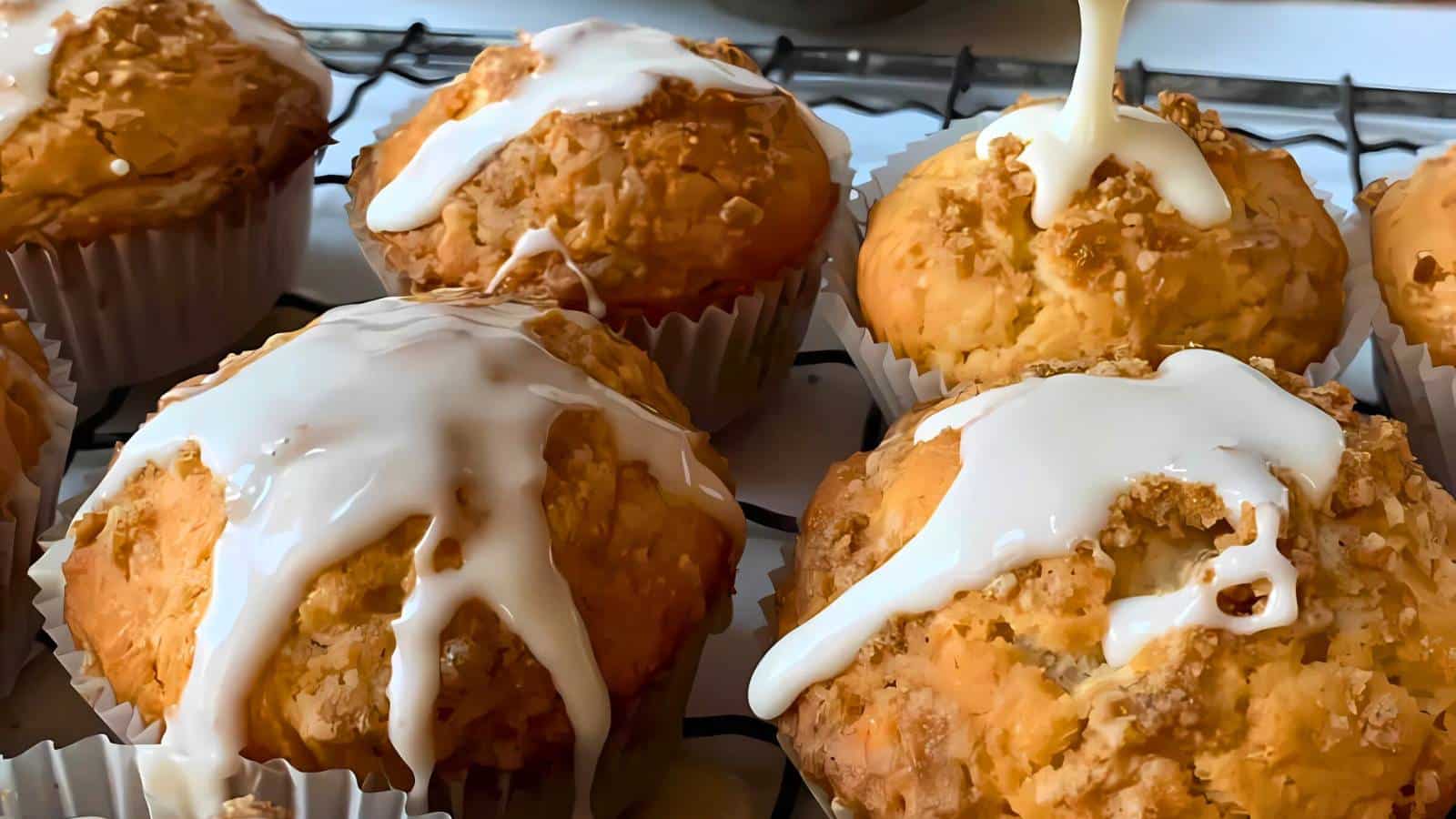 Muffins with white icing on top, cooling on a wire rack.
