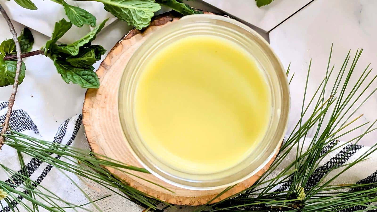 A person with a towel wrapped around their head sits against a curtain, smiling slightly.