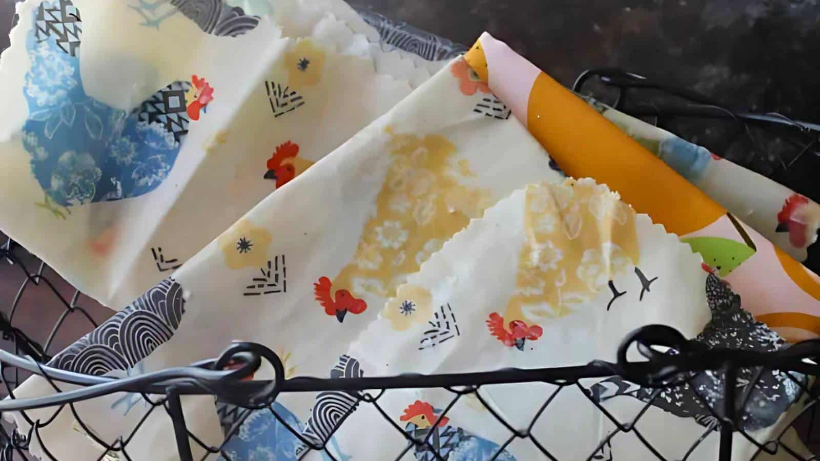 Colorful patterned wax wraps with images of chickens and foliage, placed in a black metal basket.