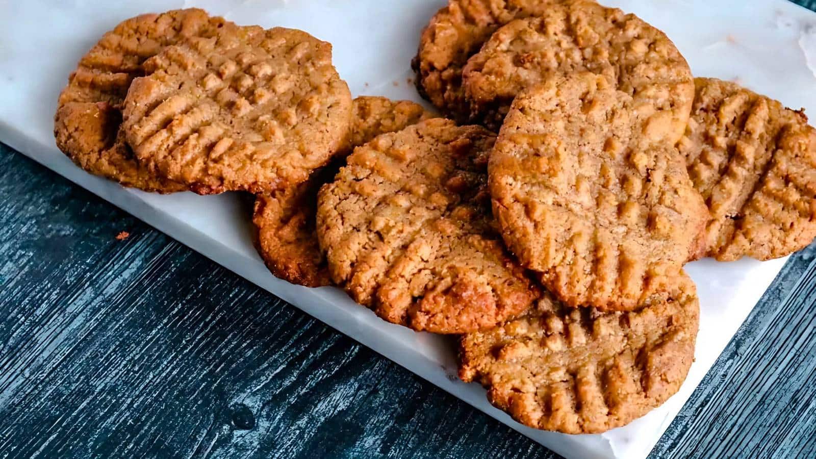 Cookies with white chocolate chunks and cranberries on a dark plate.