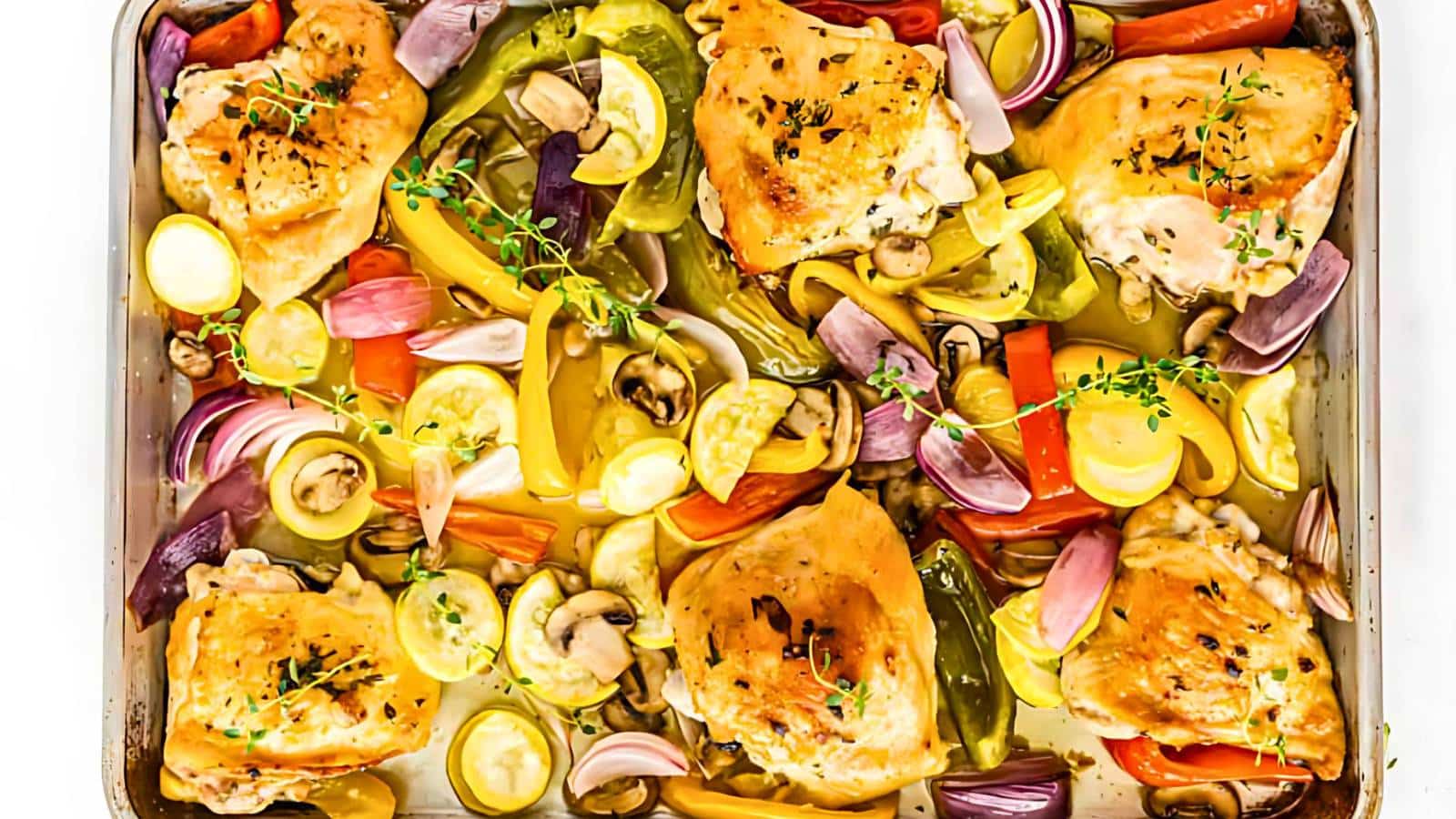 A baking sheet filled with roasted chicken thighs, yellow squash, bell peppers, onions, and mushrooms, garnished with fresh thyme.