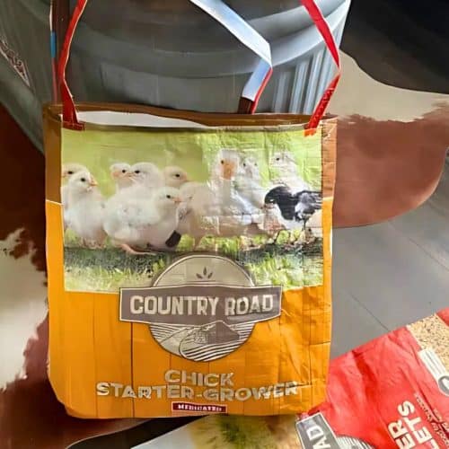 A tote bag made from a repurposed feed bag, featuring an image of chicks and the text "Country Road Chick Starter Grower.