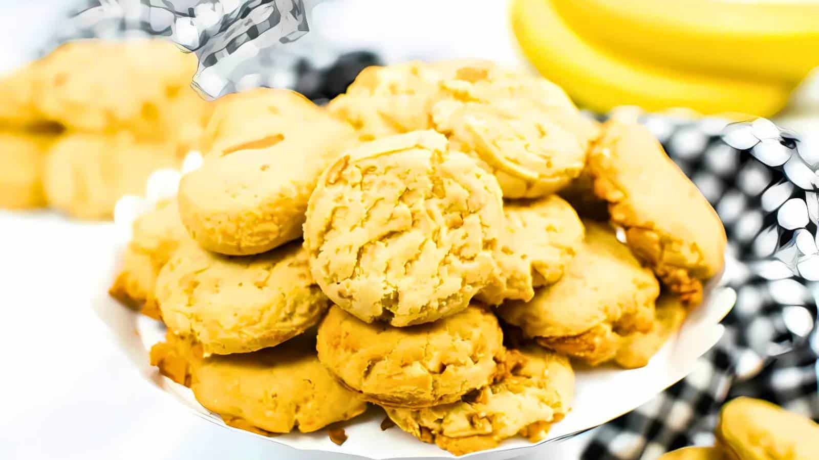 A plate filled with homemade cookies piled on top of each other, with a checkered cloth in the background.