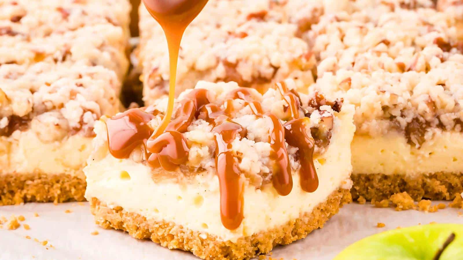 Caramel being drizzled over a slice of creamy dessert with a crumbly topping and base.