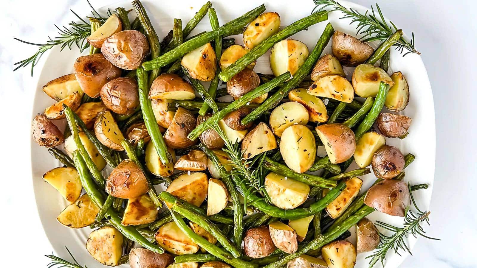 A plated dish of roasted baby potatoes, green beans, and sprigs of rosemary.