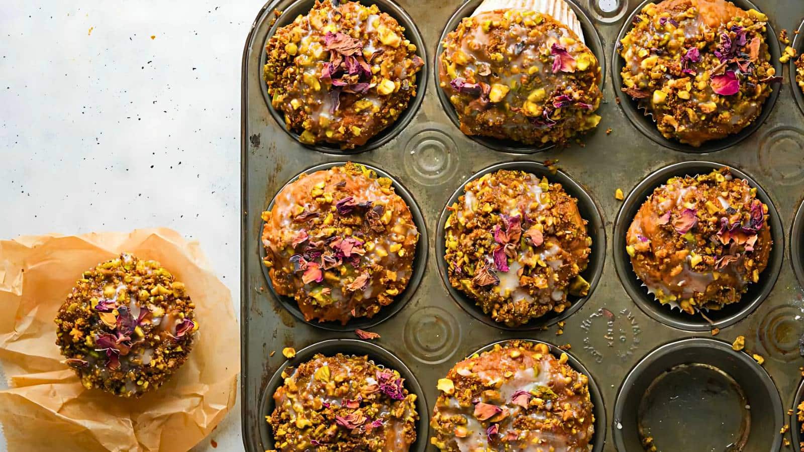 Pumpkin muffins with streusel topping and drizzle icing on a plate, surrounded by small decorative pumpkins.