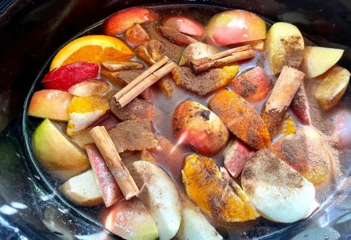 A crock pot filled with apples and cinnamon.