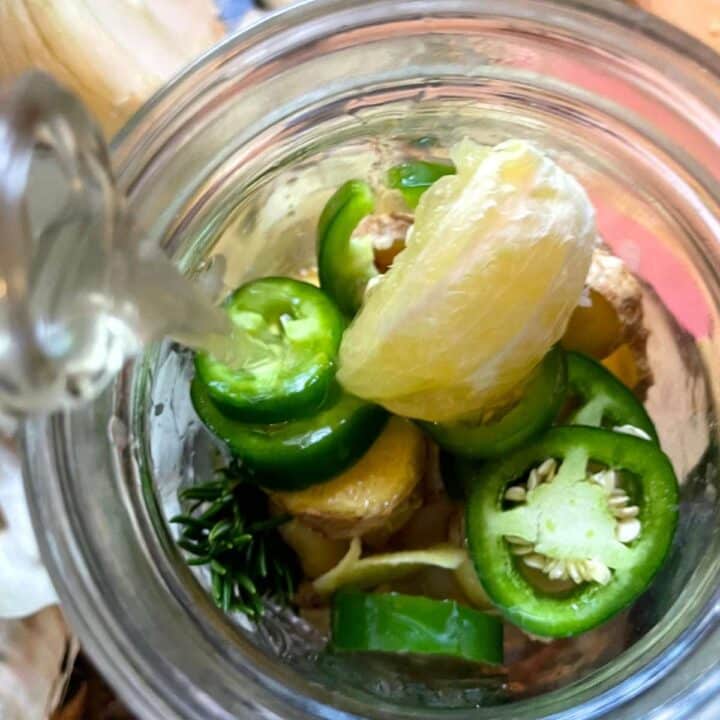 A glass jar filled with peppers and onions.
