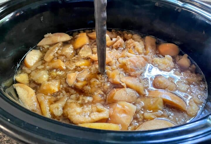 Applesauce in a slow cooker with a spoon.