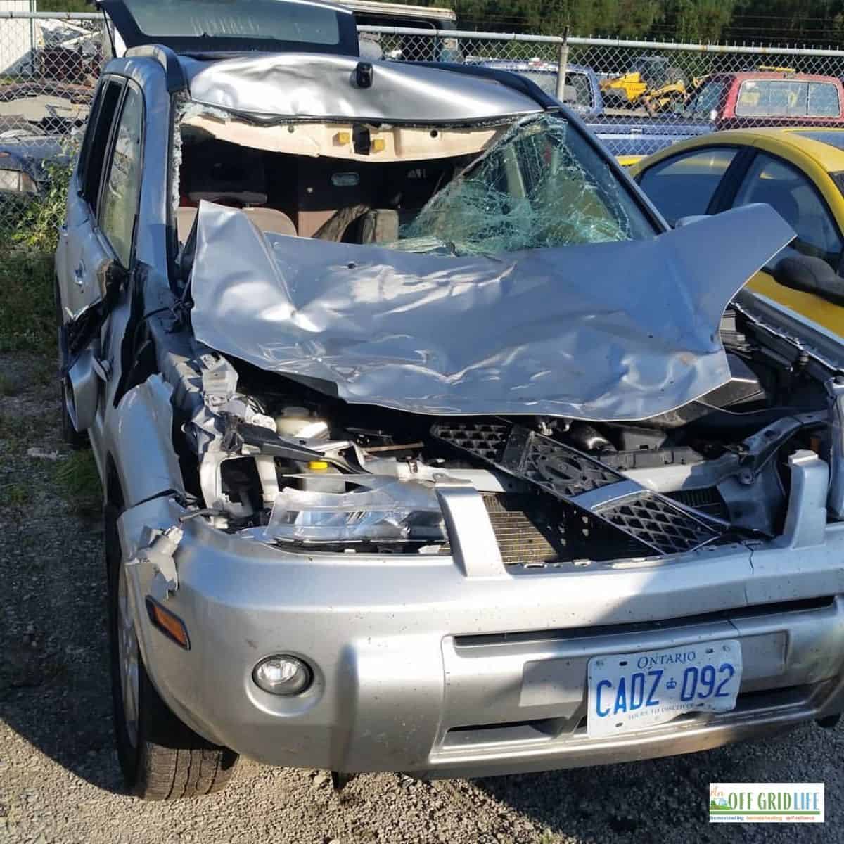 a picture of a silver suv with the front end crushed after an accident with a moose