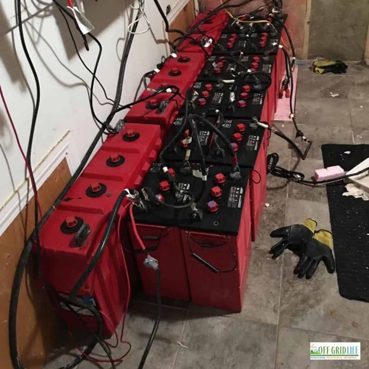 a picture of a few dozen red surrette batteries connected by cables in series.
