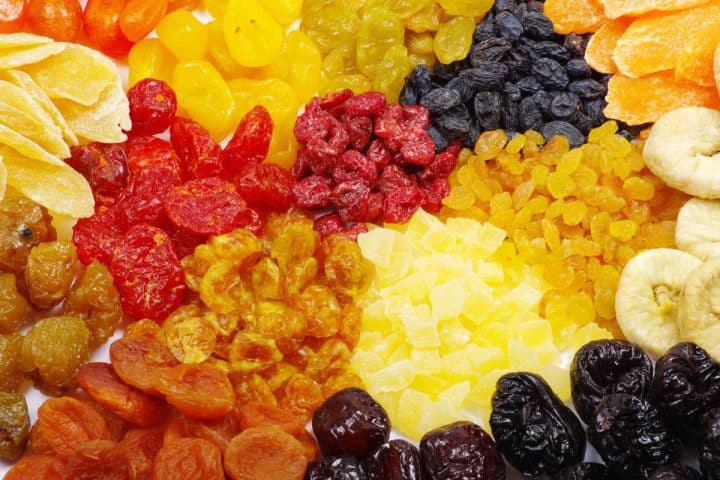 A variety of dried fruits including apricots, pineapples, cranberries, raisins, bananas, and prunes are arranged in a colorful assortment.