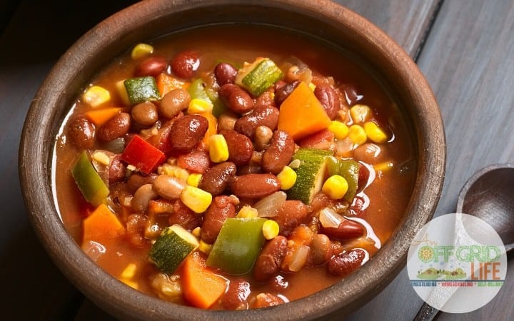 Bowl of three bean chili with vegetables including celery, peppers, carrots and corn