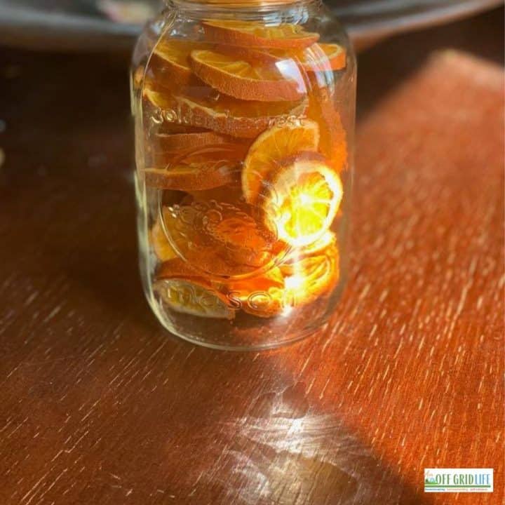 a single mason jar with dehydrated orange slices on a wooden table