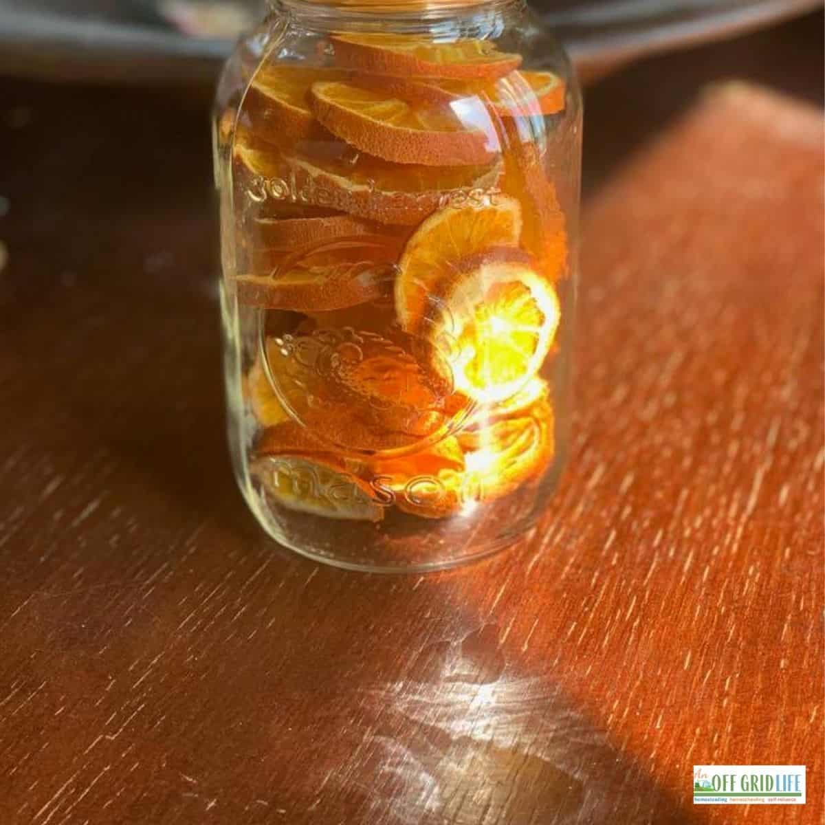 a single mason jar with dehydrated orange slices on a wooden table