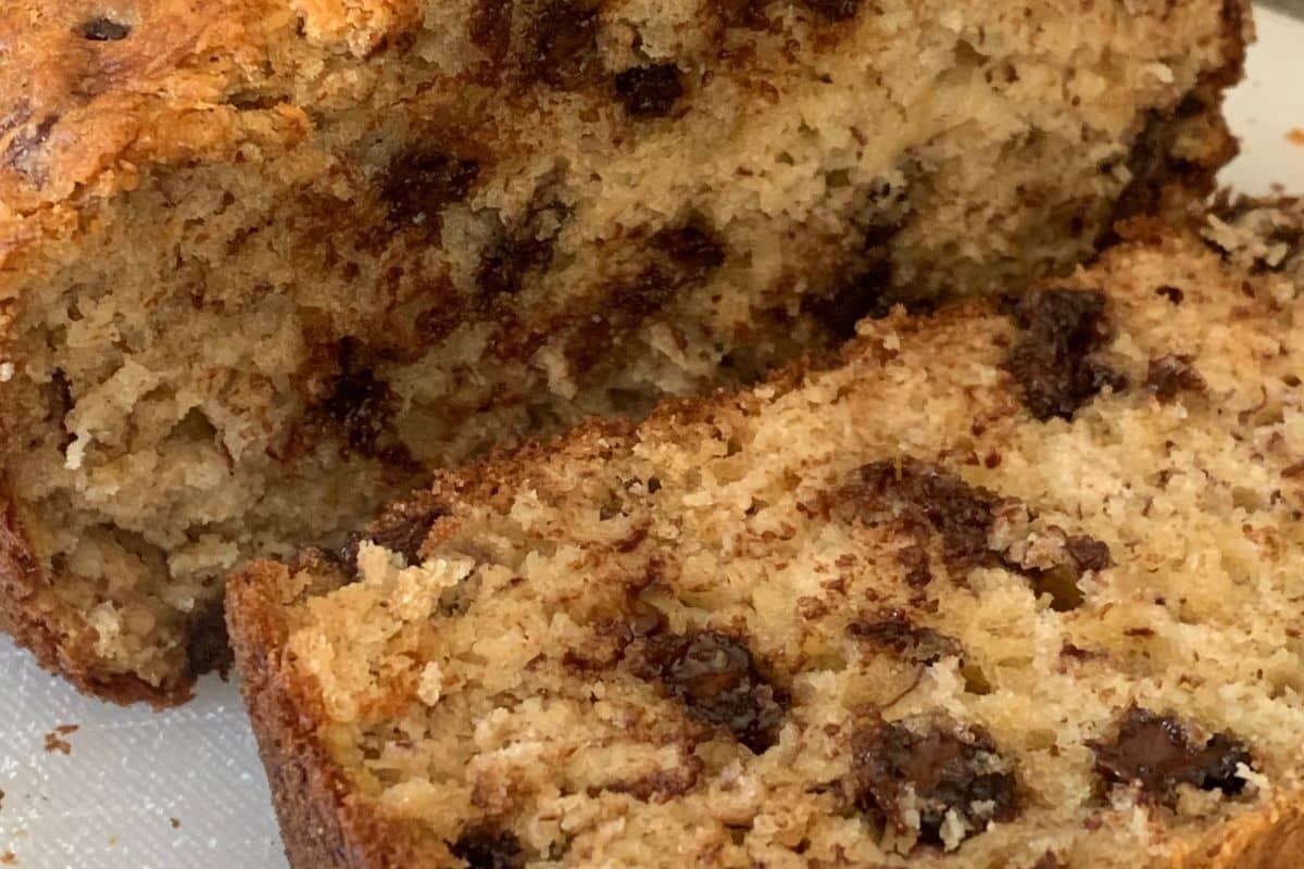 Close-up of chocolate chip banana bread on a cutting board, showing a sliced piece with visible chocolate chips and a moist, crumbly texture.