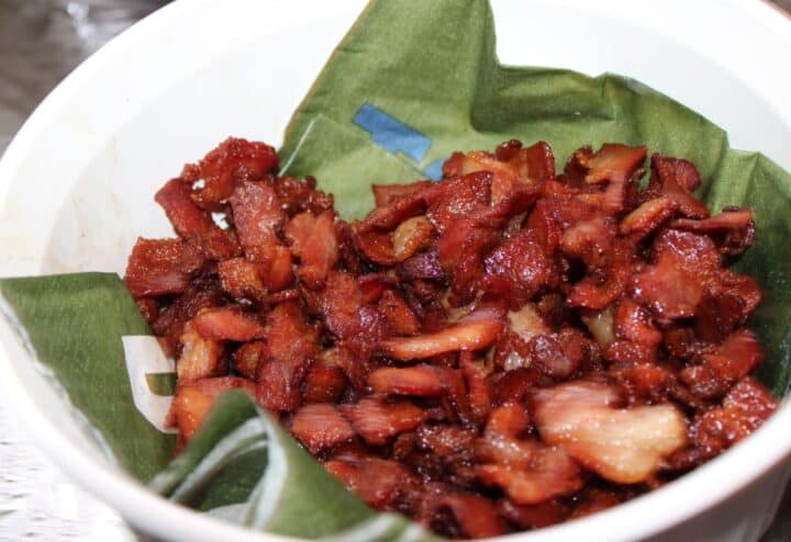 Chopped fried bacon draining on a paper napkin.