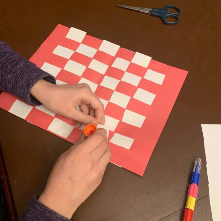 A child is creating a Christmas construction paper placemat during a Christmas craft activity.