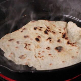 Cooking sourdough discard tortillas in cast iron skillet.
