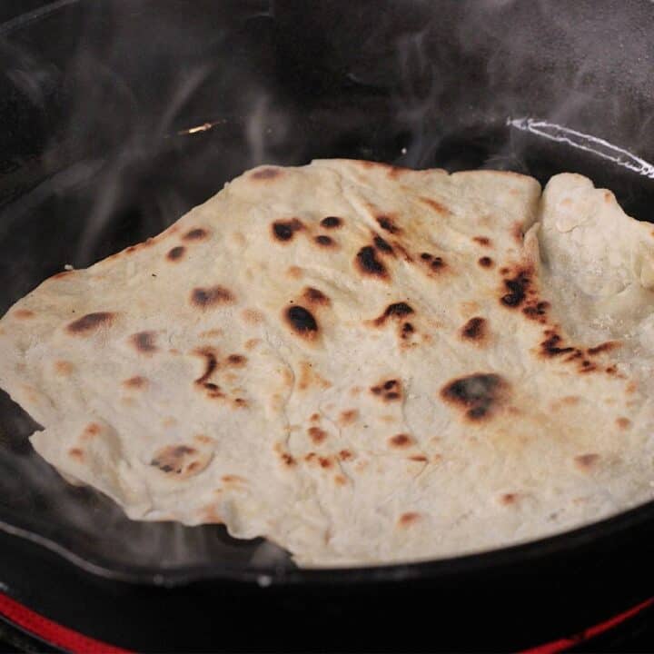 Cooking sourdough discard tortillas in cast iron skillet.