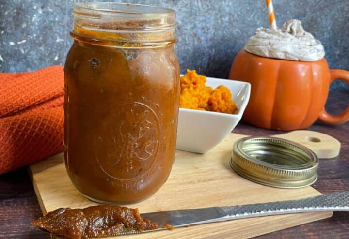 Pumpkin butter in a mason jar on a cutting board.