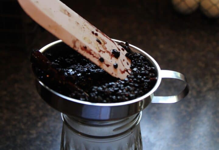 A spoon is being used to stir something in a glass.