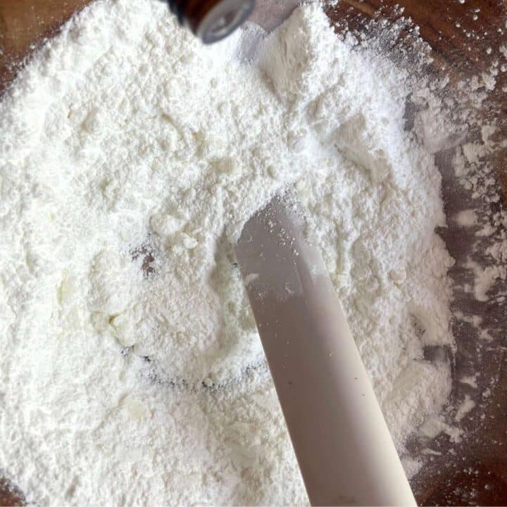 A person mixing ingredients in a wooden bowl to make shower steamers.