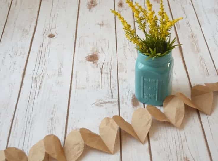 Festive pioneer Christmas crafts for kids - create a charming paper heart garland with floral accents displayed in a classic mason jar.