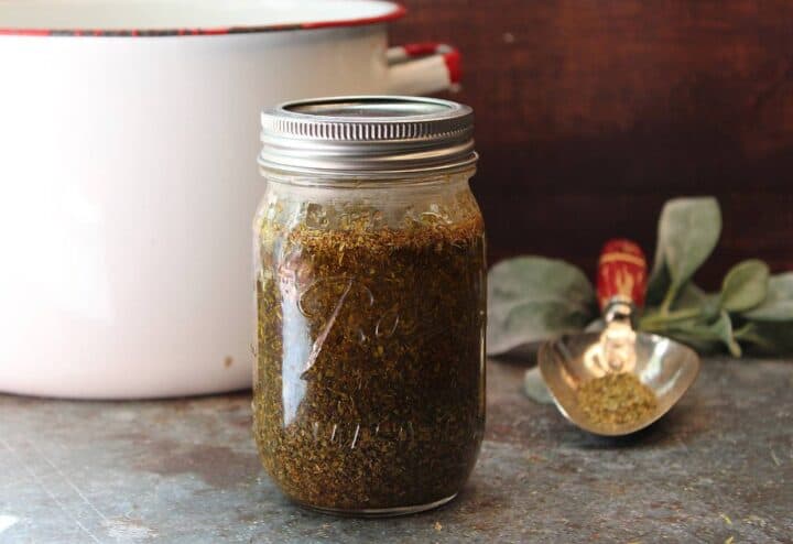 DIY oregano oil in mason jar with trowel and pot in background.