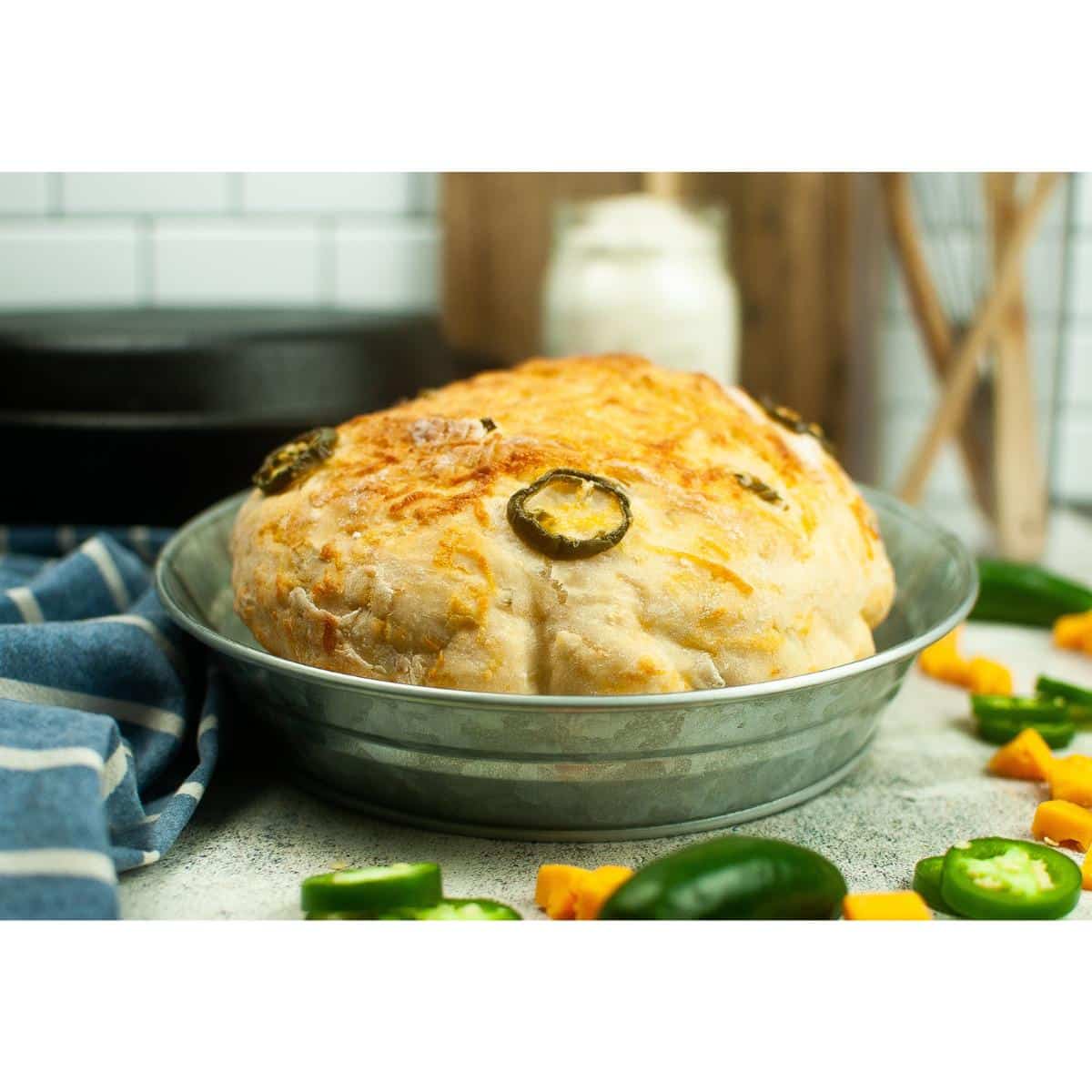 A loaf of dutch oven jalapeno cheddar bread with jalapeno peppers.