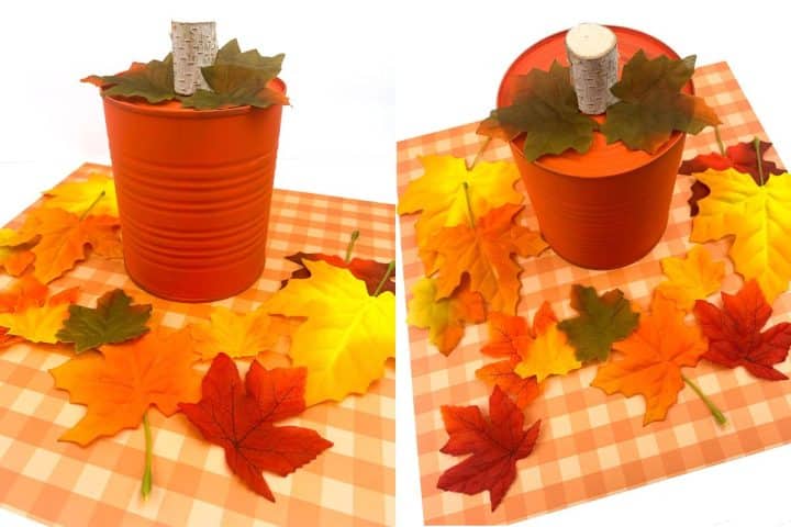 Orange tin can decorated with artificial autumn leaves and a faux birch branch on a checkered cloth backdrop.