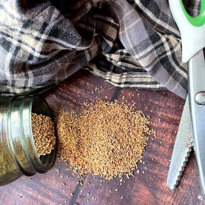A jar of grains seeds next to a pair of scissors and a piece of plaid cloth to make eco-friendly hand warmers.
