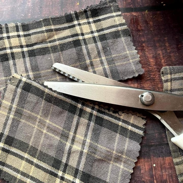 A pair of scissors on a piece of plaid fabric.