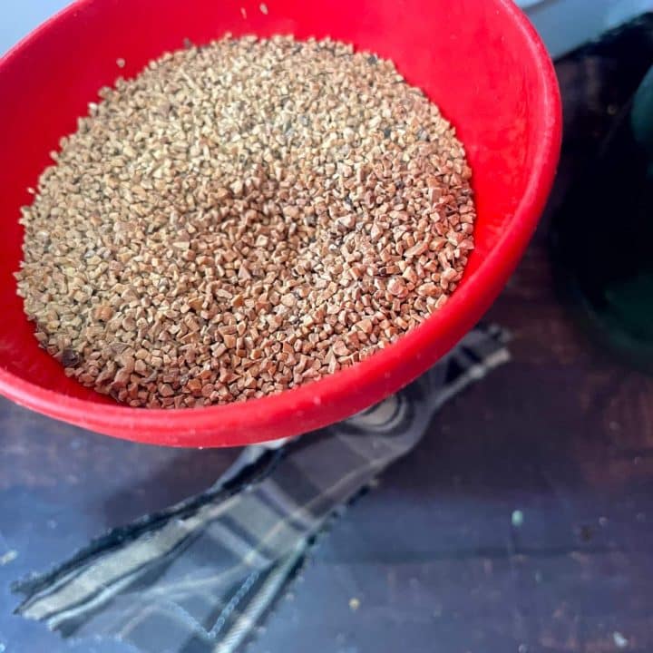 Buckwheat groats in a red bowl on a wooden table.