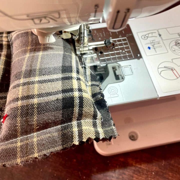 A sewing machine is being used to sew a plaid fabric.