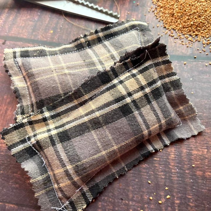 A pair of plaid fabric pillows on a table next to a pair of scissors.